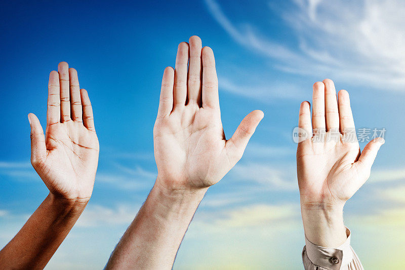 Hands waving or making the Stop gesture, held aloft against a summer sky with a dusting of cloud